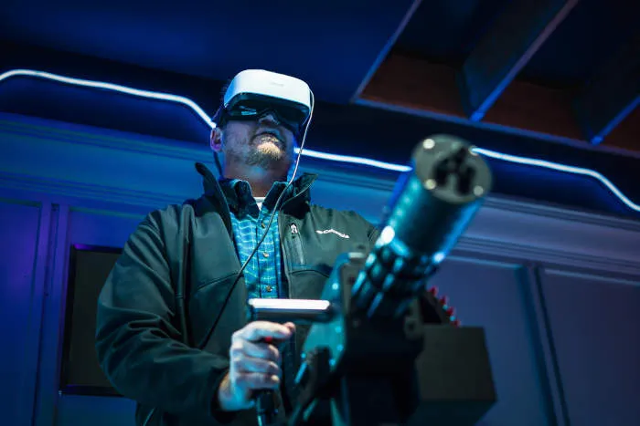 Man holding a gatling gun controller with a VR headset